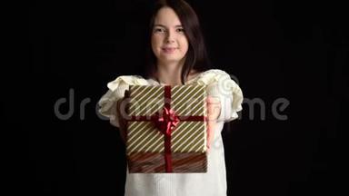年轻女子在黑色背景上赠送礼品盒.. 带白色丝带的礼品盒，祝新年快乐，圣诞快乐